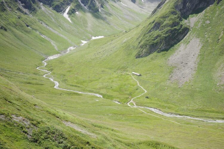 Ruisseau serpentant dans une vallée dans les Alpes